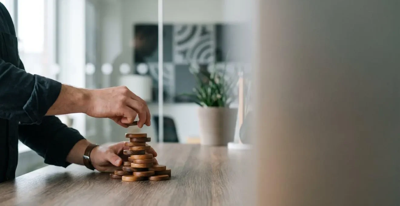 Mains d'un entrepreneur empilant des piles de pieces representant la progression de l'epargne personnelle vers l'apport en fonds propres