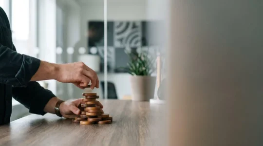 Mains d'un entrepreneur empilant des piles de pieces representant la progression de l'epargne personnelle vers l'apport en fonds propres